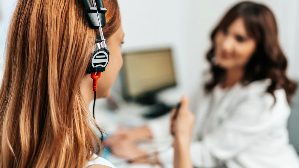 Audiologist fitting headphones for a hearing test at The Hearing Team clinic in Birmingham
