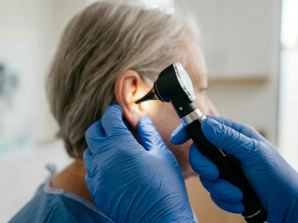Audiologist examining a patient's ear with an otoscope before earwax removal at The Hearing Team clinic in Birmingham